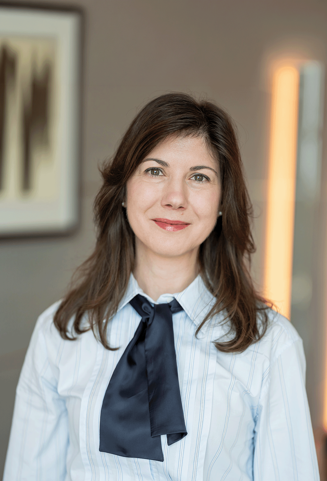 Roxana Apostol mit schulterlangen Haaren, Bluse und Halstuch, die lächelnd in die Kamera schaut