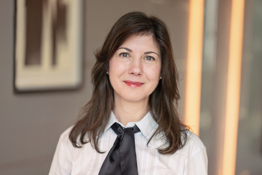 Roxana Apostol mit schulterlangen Haaren, Bluse und Halstuch, die lächelnd in die Kamera schaut
