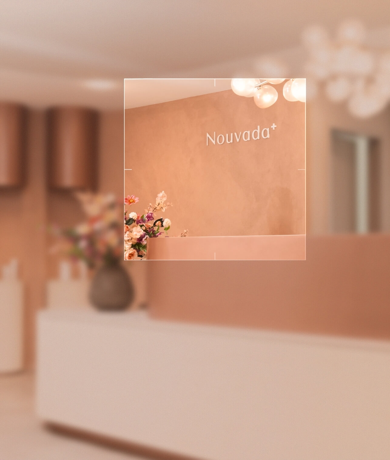 Empfangsbereich mit Theke, Blumenstrauß in Vase und Schriftzug Nouvada an der Wand